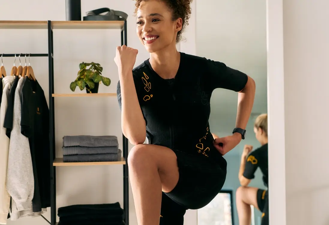 Een vrouw in een EMS-pak doet een intensieve indoor workout met EMS-training voor effectief afvallen en vetverbranding.
